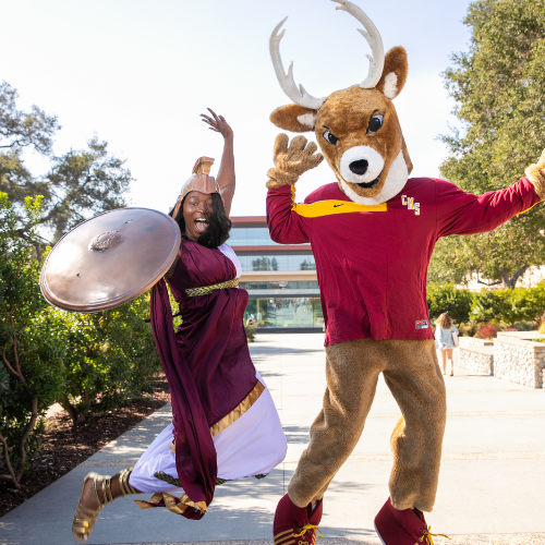 A student dressed as the Athena mascot alongside the Stag mascot.