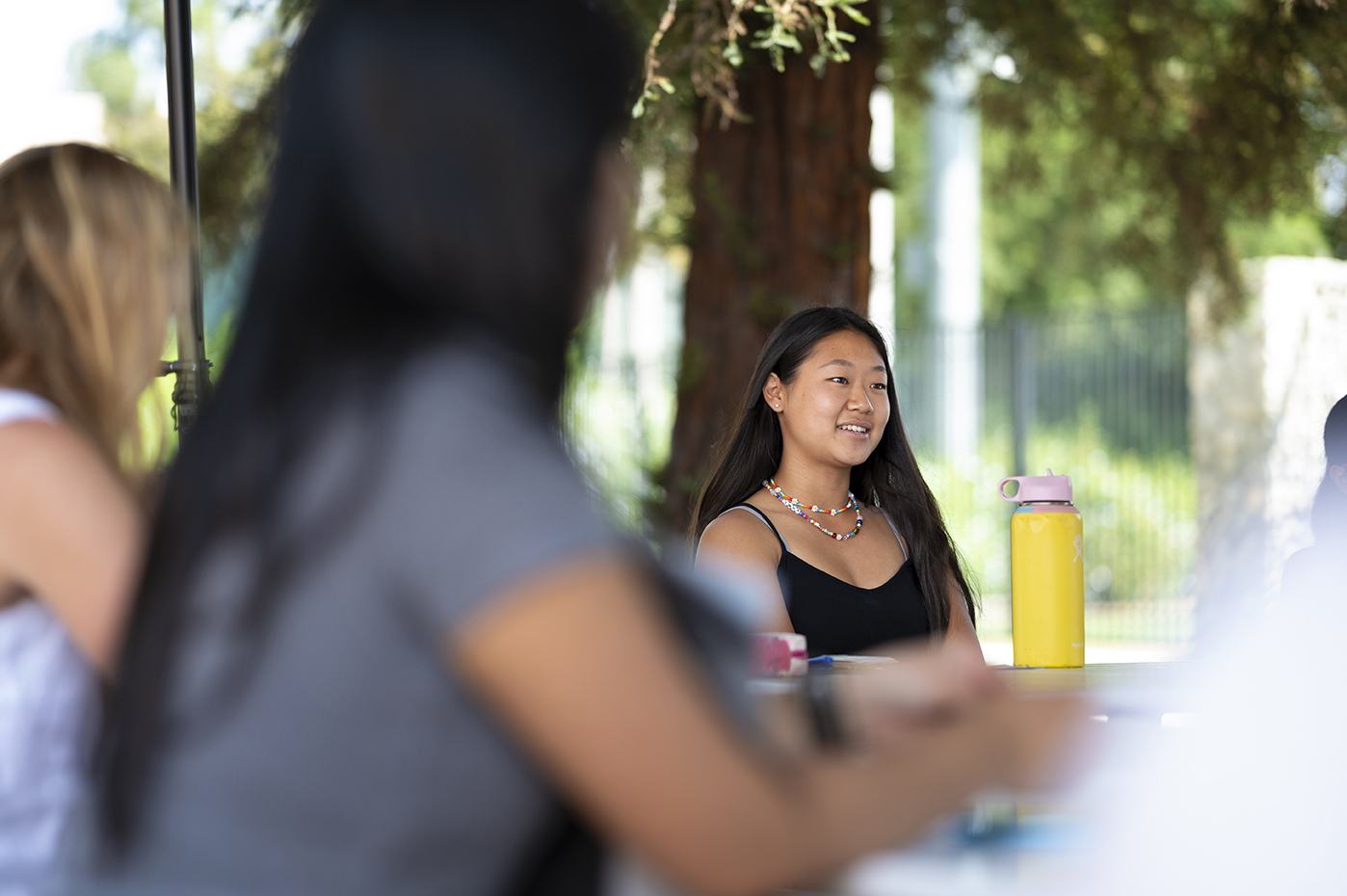 Students sitting around an outdoor classroom in sunny weather