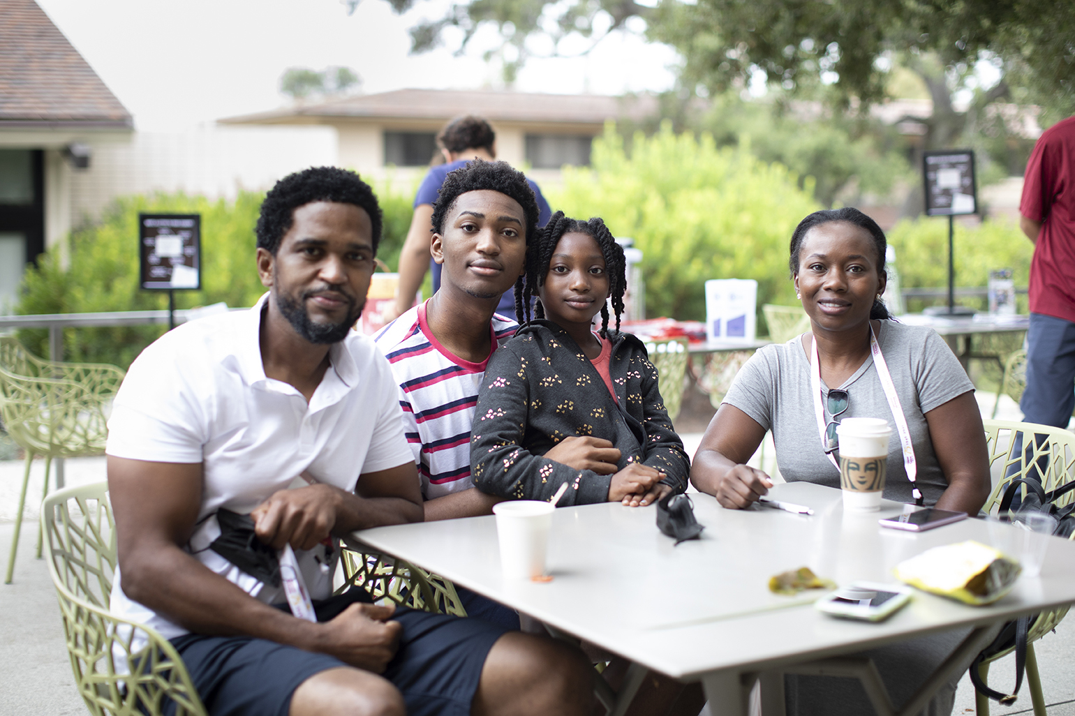 Gio Pierre ’25 (middle) seated at an outdoor table on campus surrounded by his family