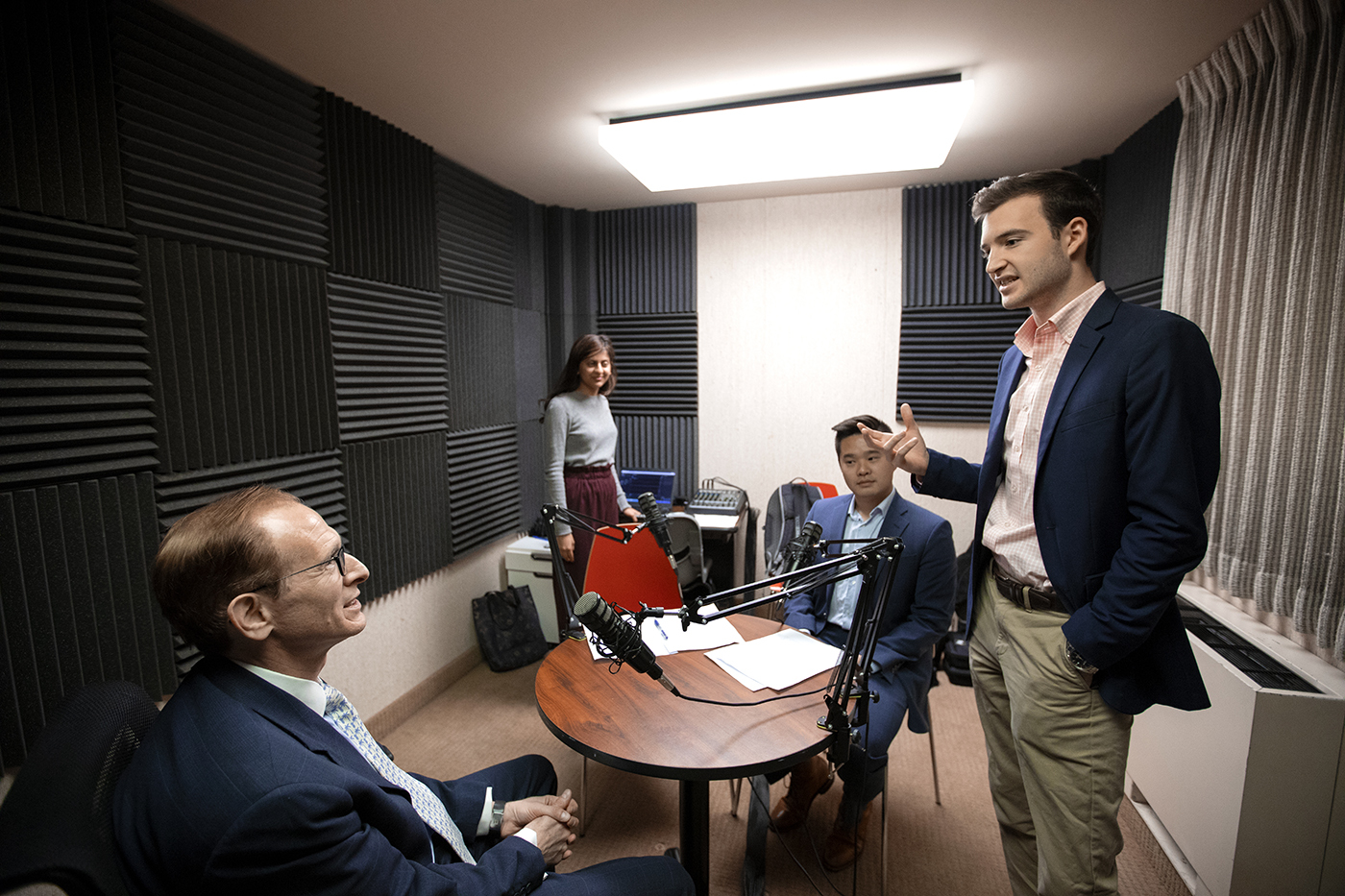 Students of Free Food for Thought gather around in the recording room with a guest in preparation of another episode.