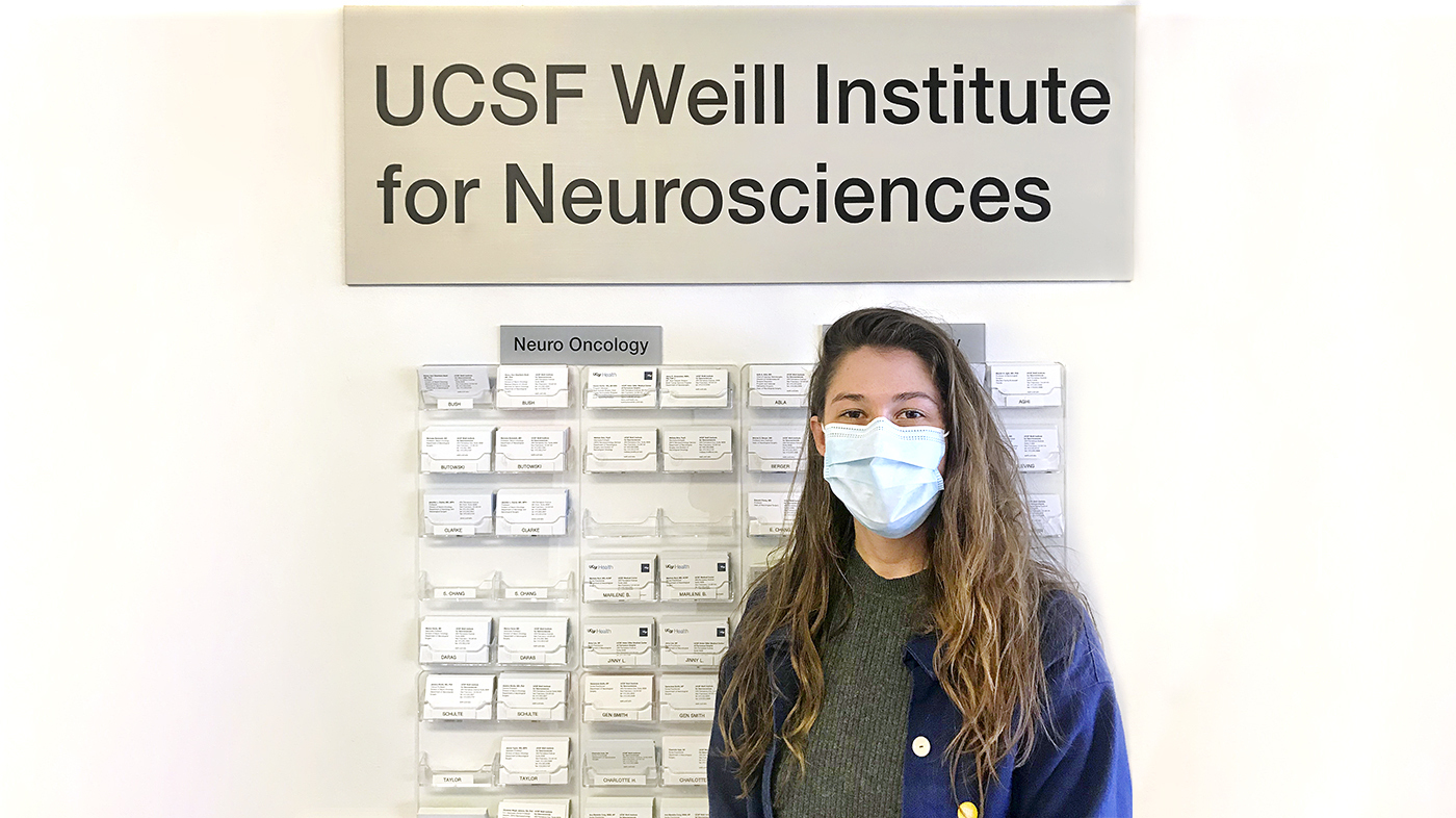 Anya Zimmerman-Smith ’21 poses with her mask on in front of her Honor Project board at UCSF Weill Institute for Neurosciences