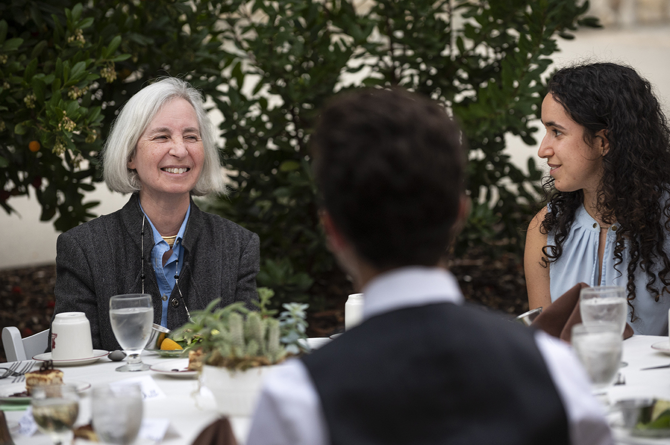 Martha Minow smiles with students at the head table during Ath outdoor dinner