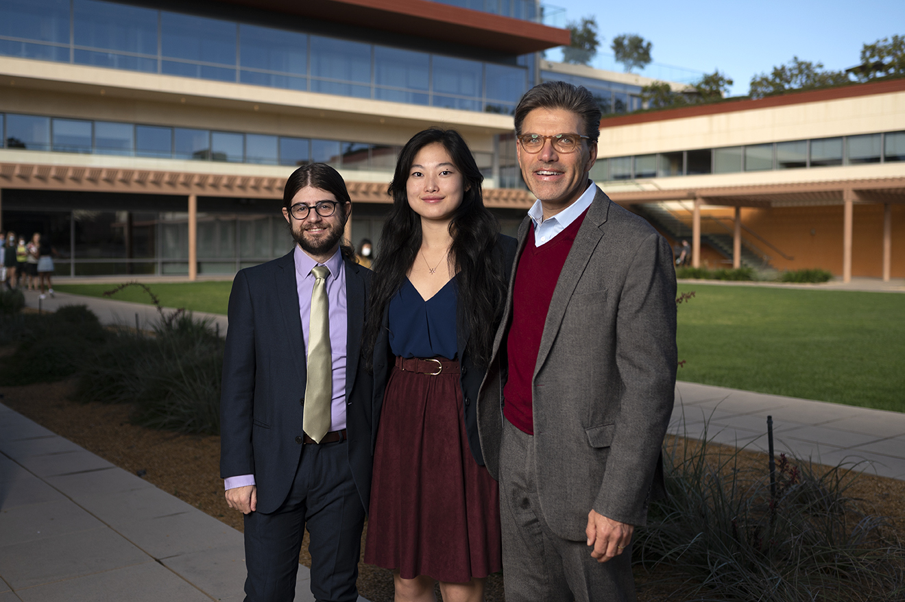 From left to right: Brian Davidson '08, Sarah Chen '22, and President Chodosh stand arm in arm in front of the Kravis Center.