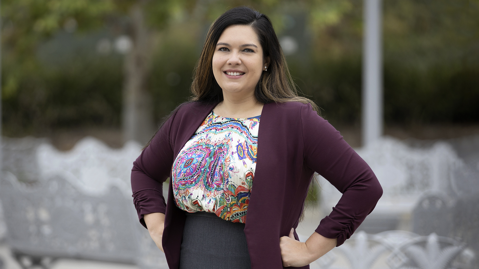 Portrait of CMC Prof. Jennifer Feitosa with her arms akimbo on campus.