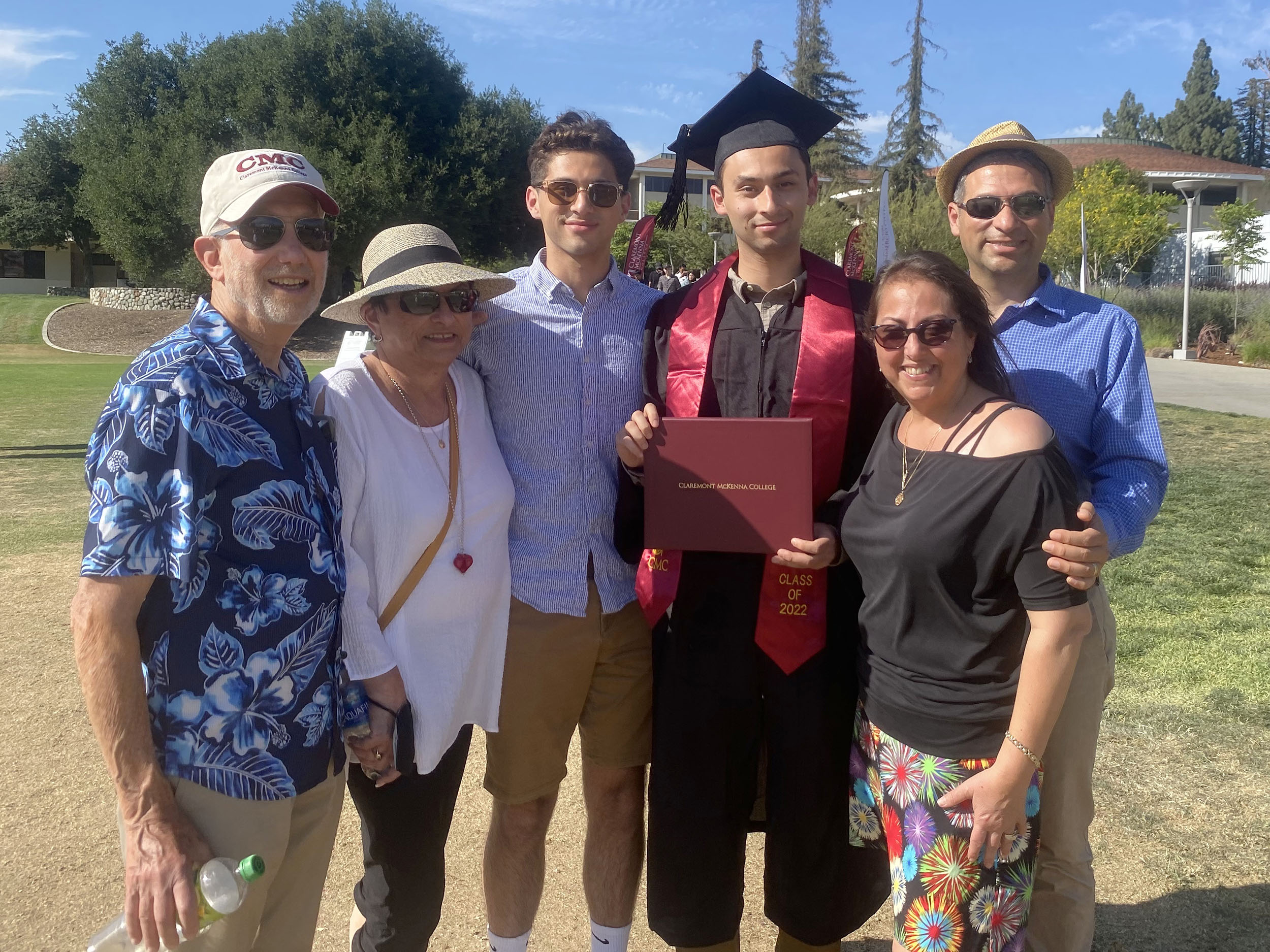 Matias Alvarado ’22 holds up his diploma, surrounded by family at CMC's 2022 Commencement.