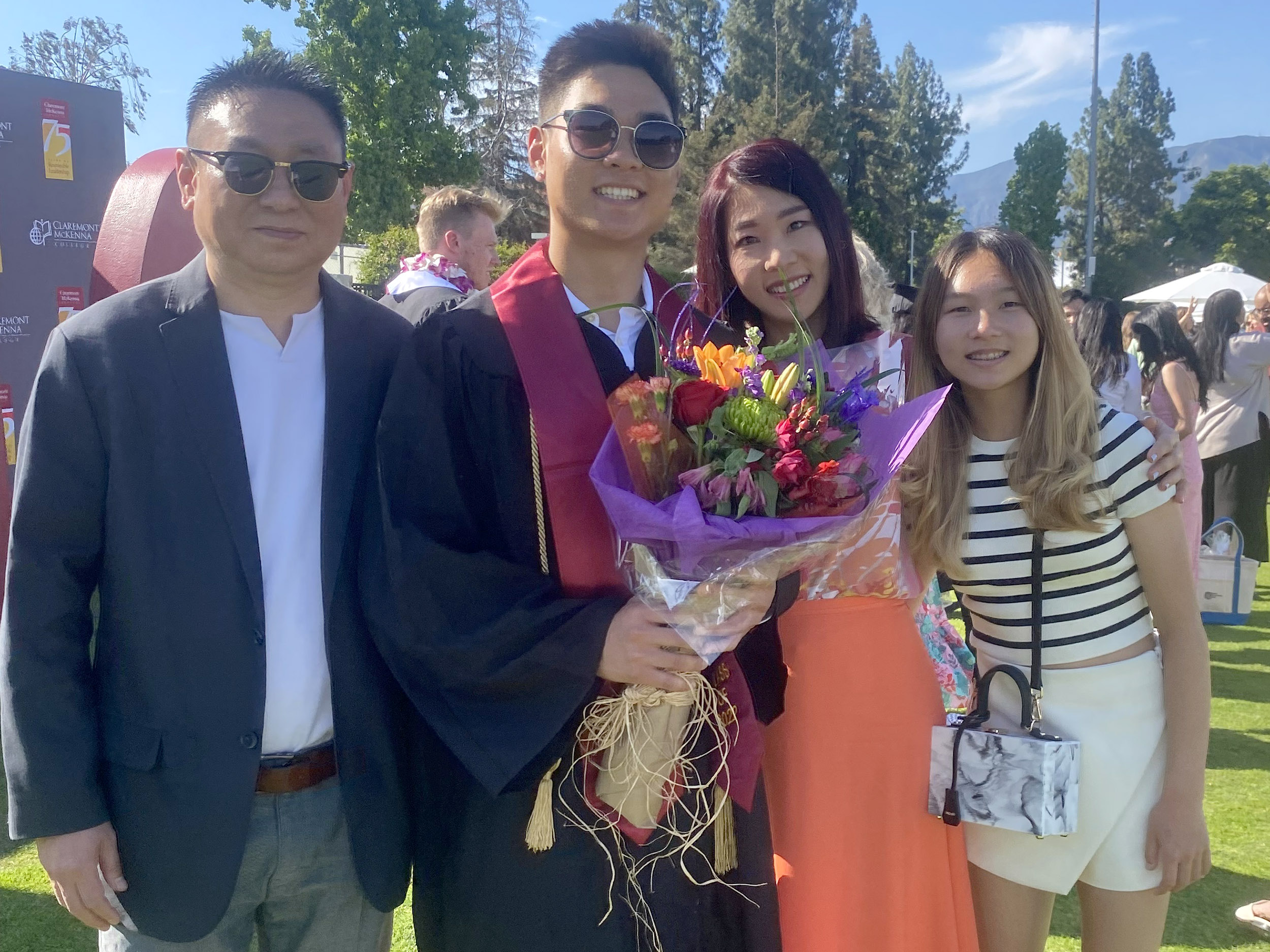 Calvin Koo ’22 stands surrounded by his family out on the field during CMC's 2022 Commencement.