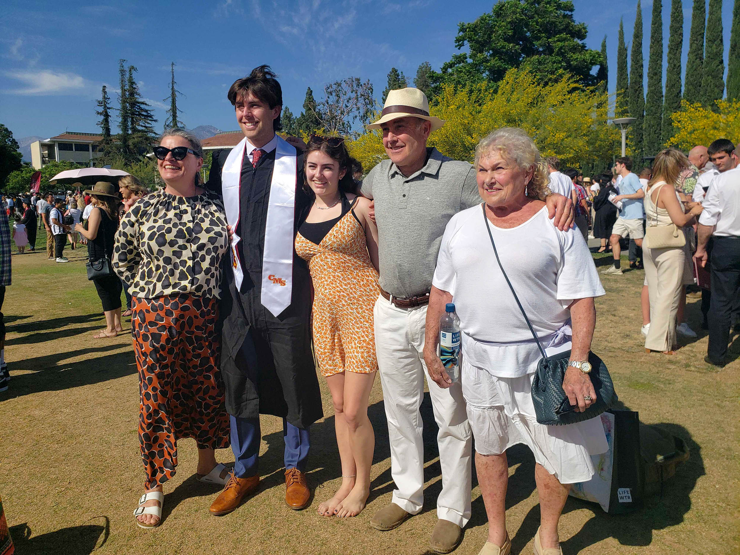 Harper Rubin ’22 arm in arms with his family on Parents Field for CMC's 2022 Commencement.