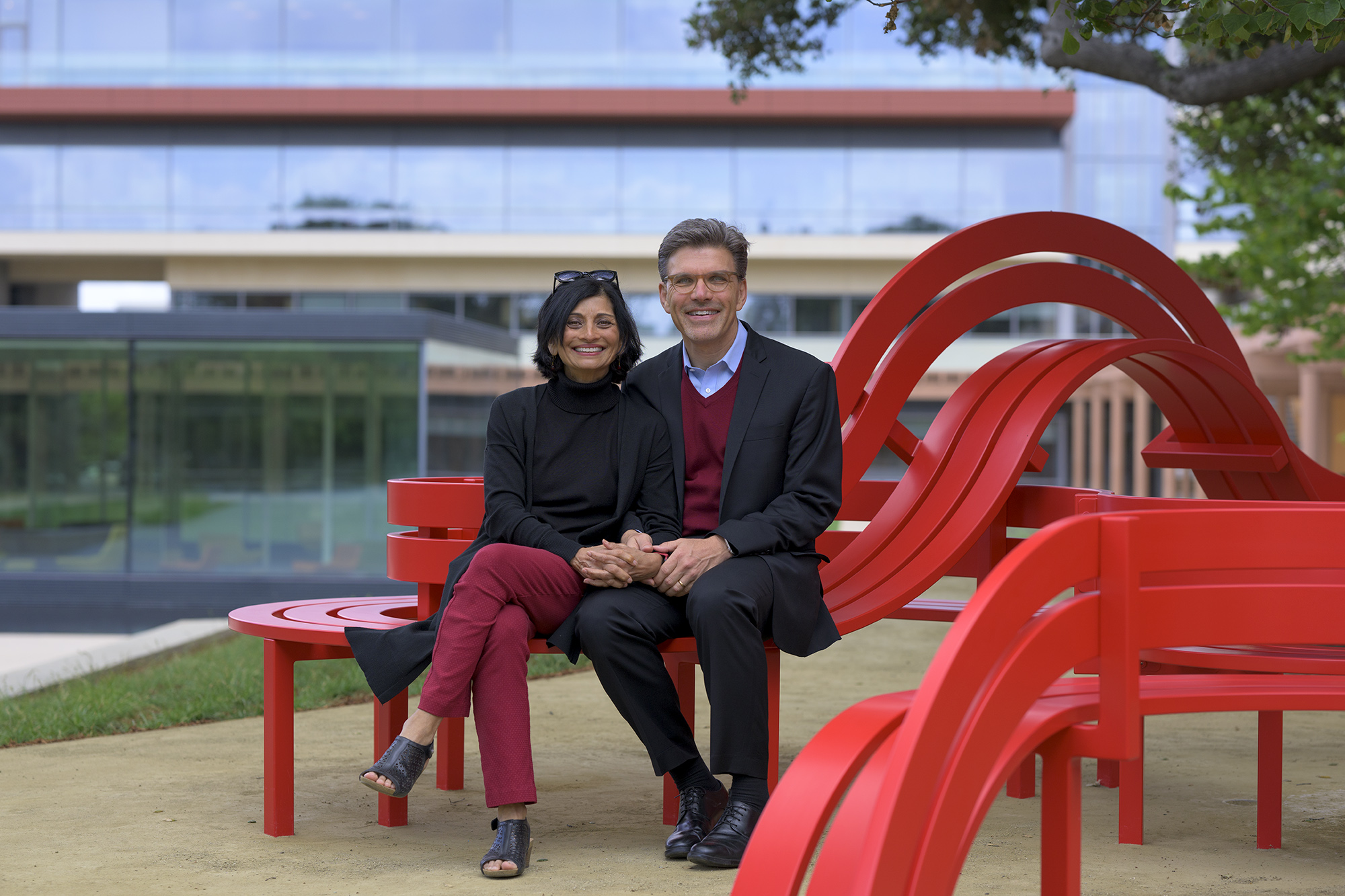 Priya Junnar and President Hiram Chodosh sit together on the benches. Behind them is the Kube and Kravis Center.