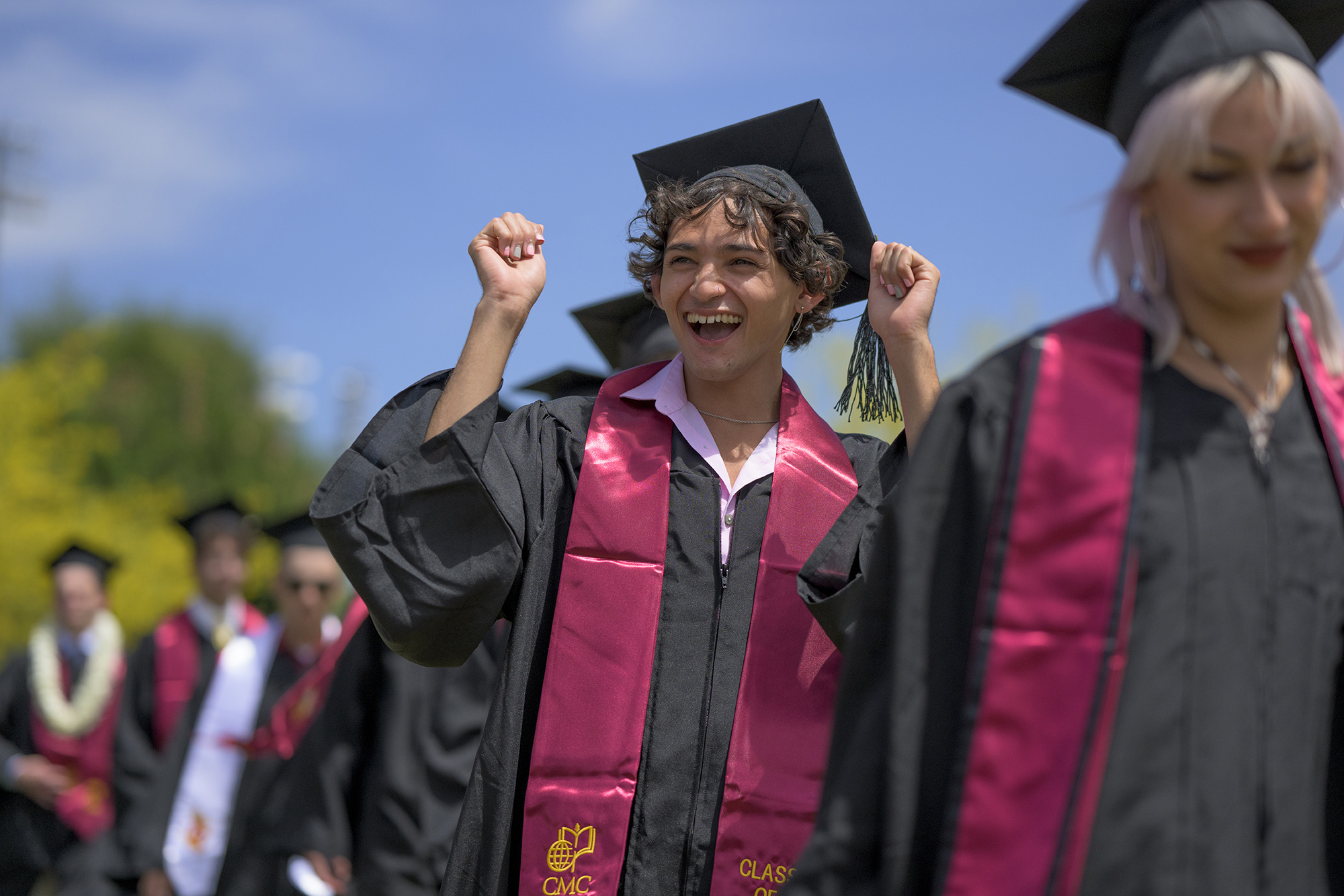 A CMC graduate pumps their fists as they proceed into the tent on Parents Field for 2022 Commencement.