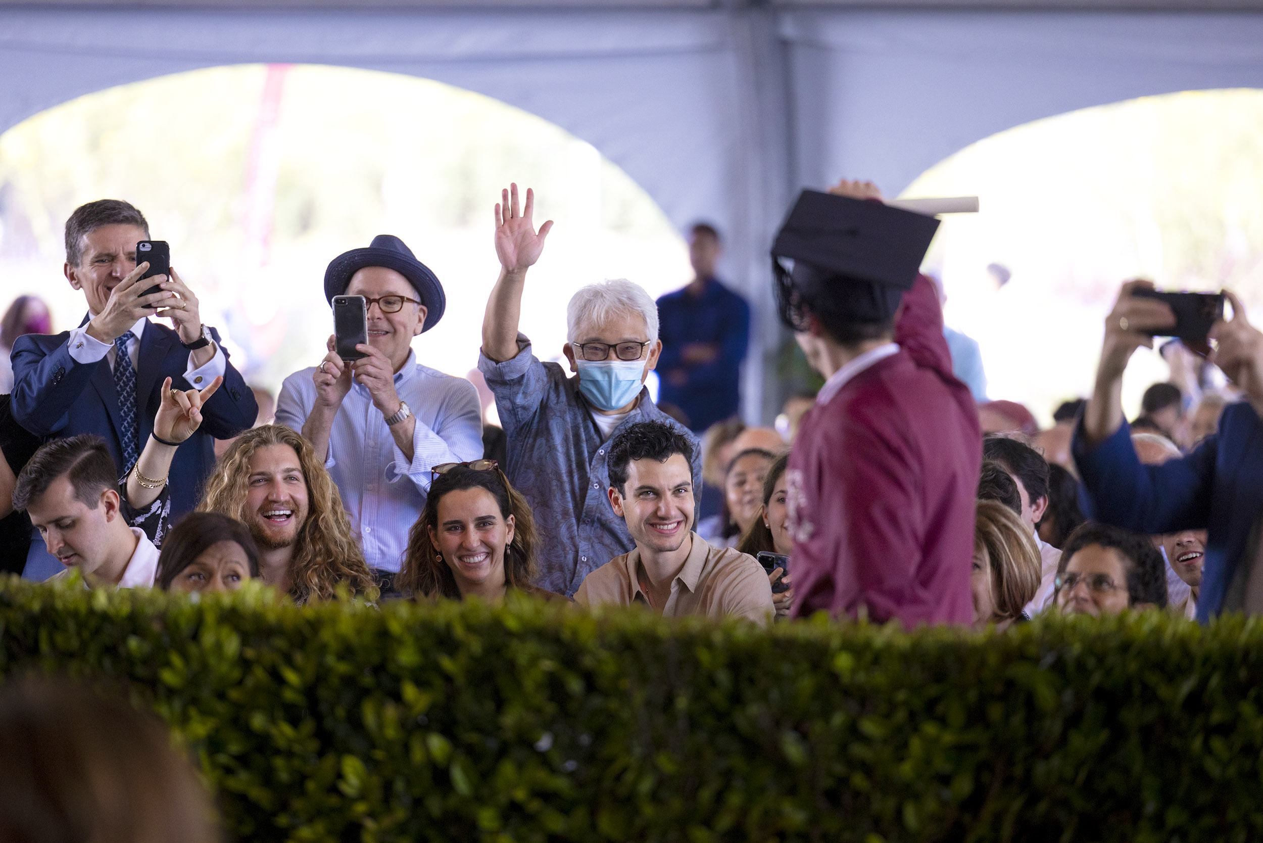 A grad waves to cheering families and friends after receiving their diploma.