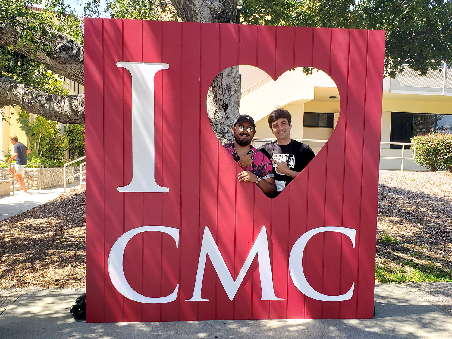 Alan Hernandez ’20 and Justin Estrada ’20 pose together behind the red "I [heart] CMC" photo prop frame.