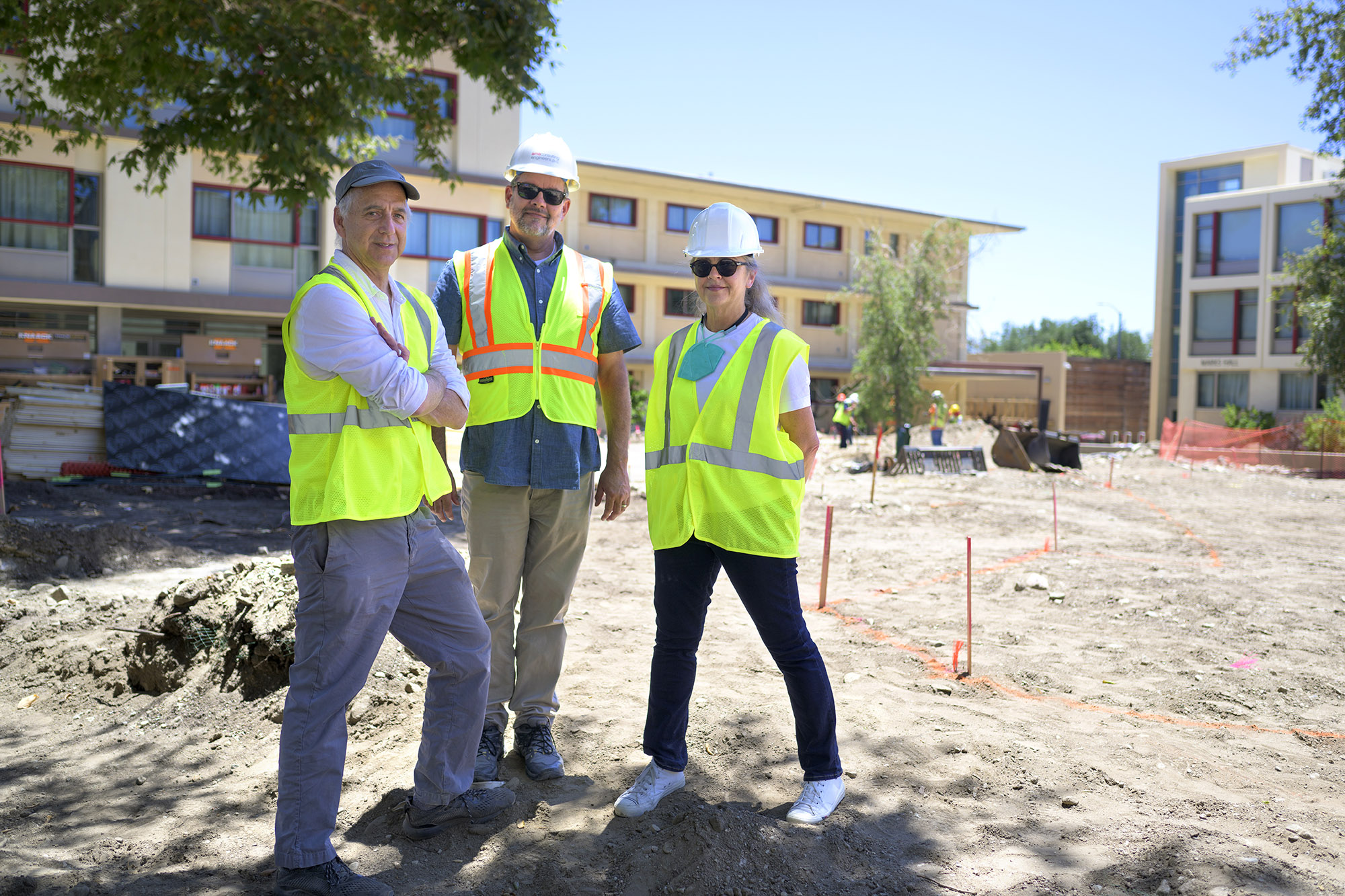 Architect and lighting principals stand on the open construction site on Mid-Quad with the artist Pae White, wearing safety vests and hard hats.