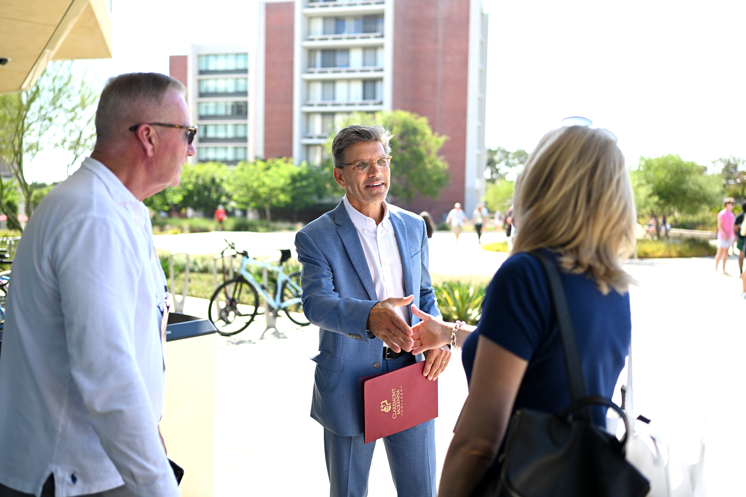 President Chodosh (middle) reaches out for a handshake with parents outside Roberts Pavilion.