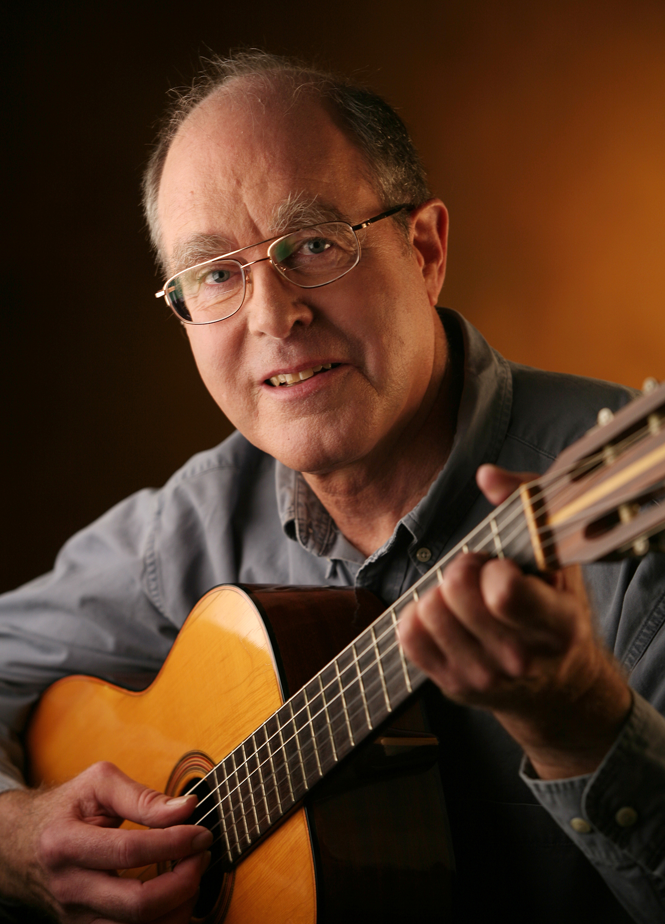 Professor Ward Elliott photographed holding a guitar.