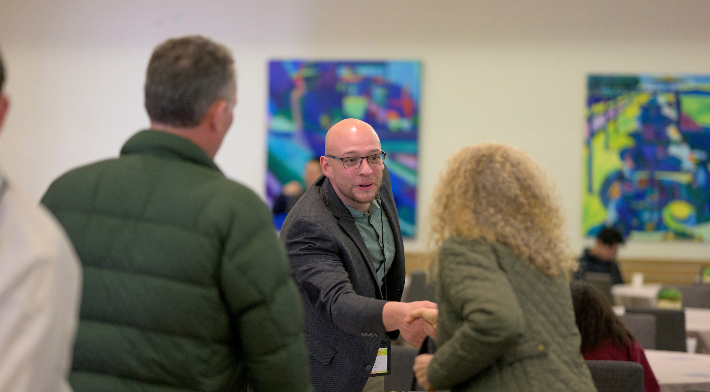 Man shaking hands with visitors at KLI conference.