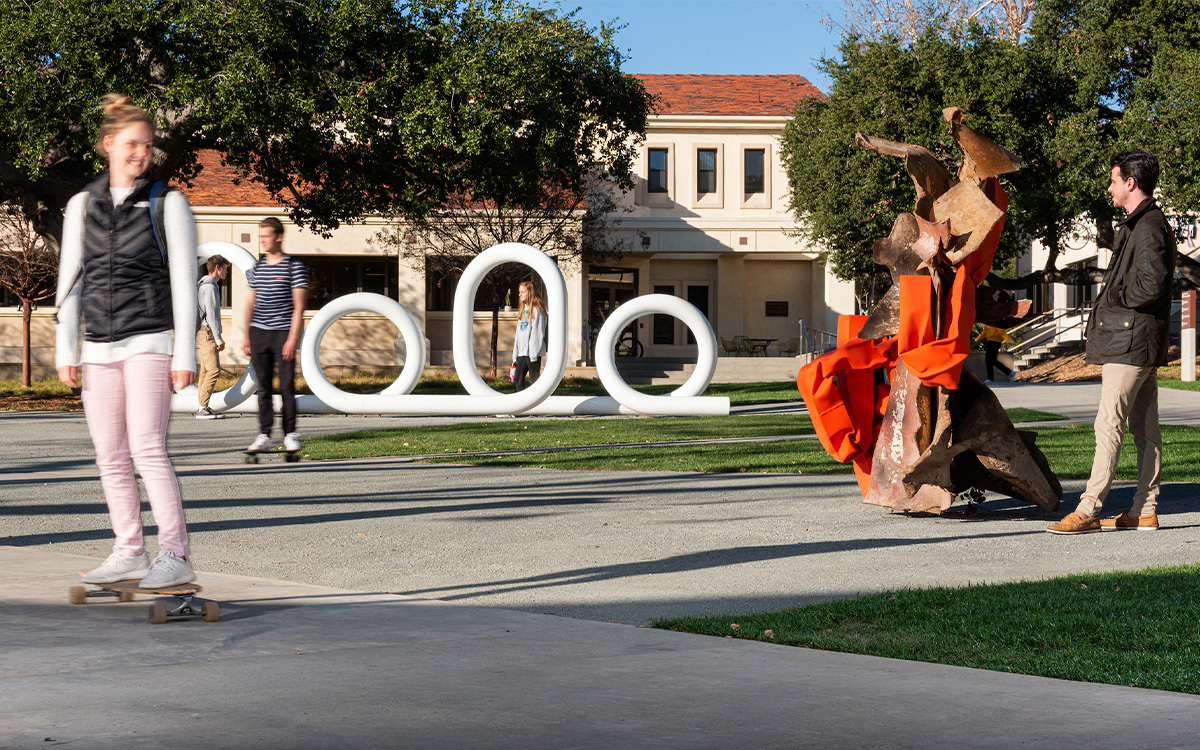 A student skateboards past two of Carol Bove's sculptures.