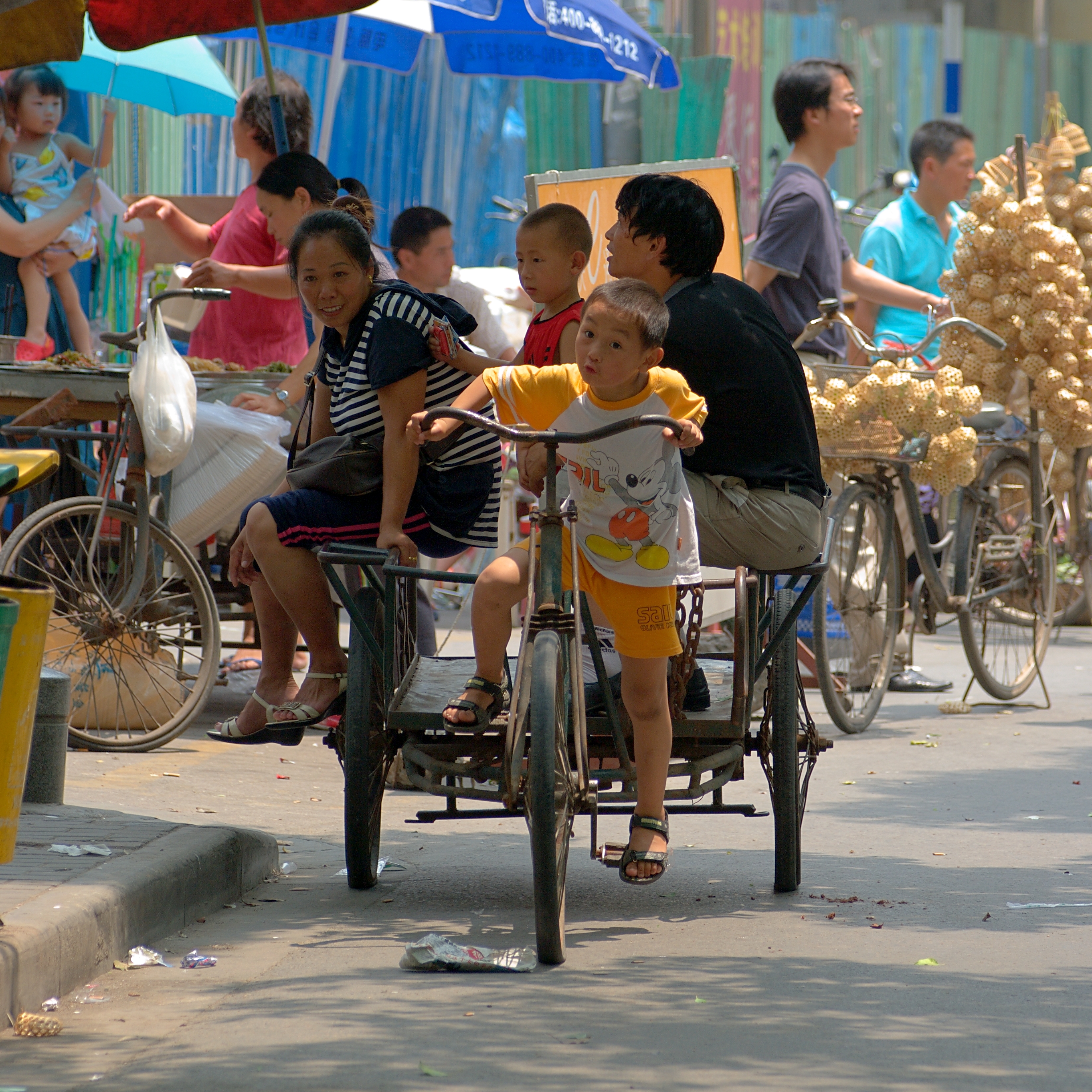 Child riding pedaled cart with family sitting in back seats