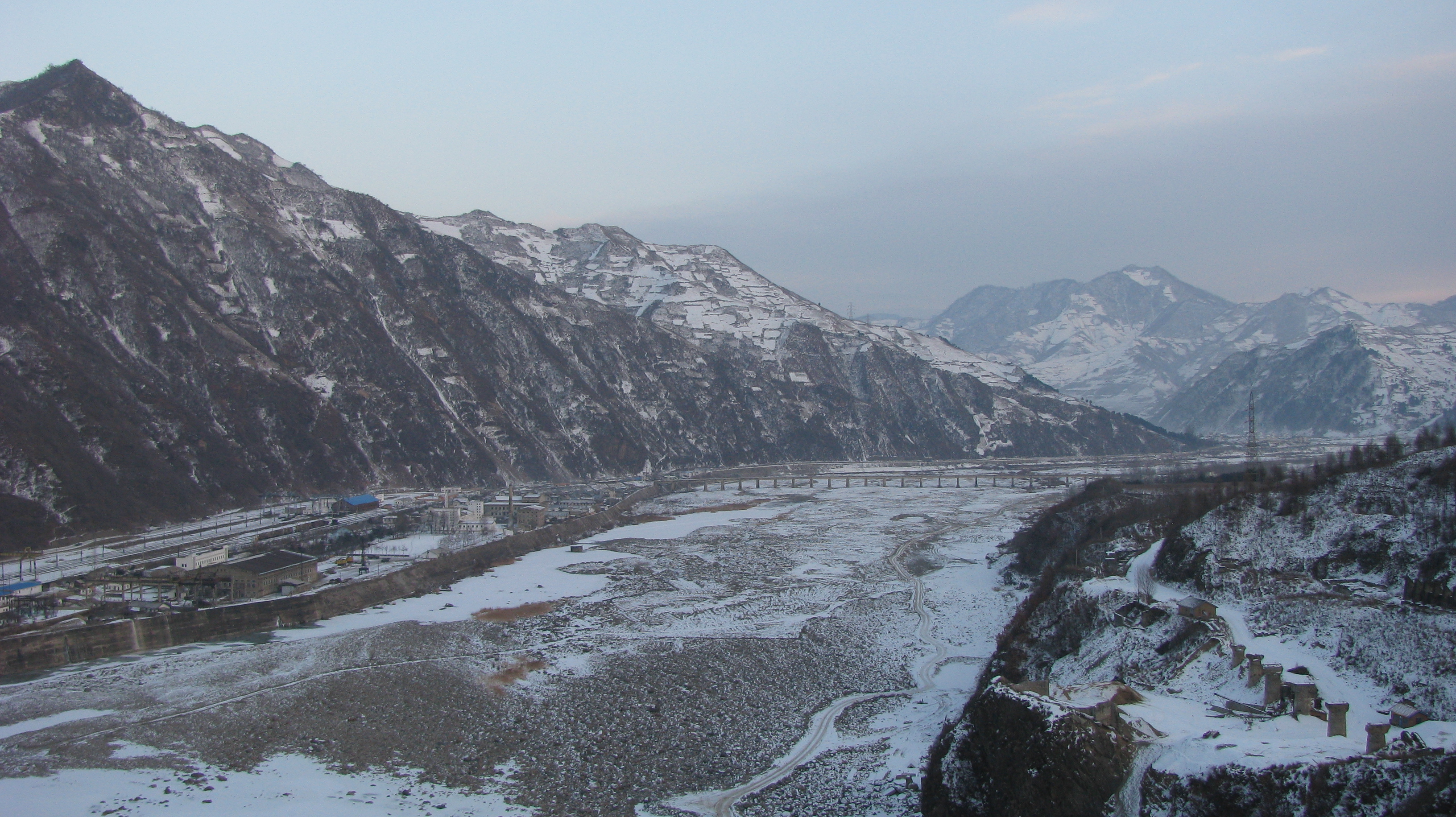 Photograph of the Yalu River with a railway bridge and a factory