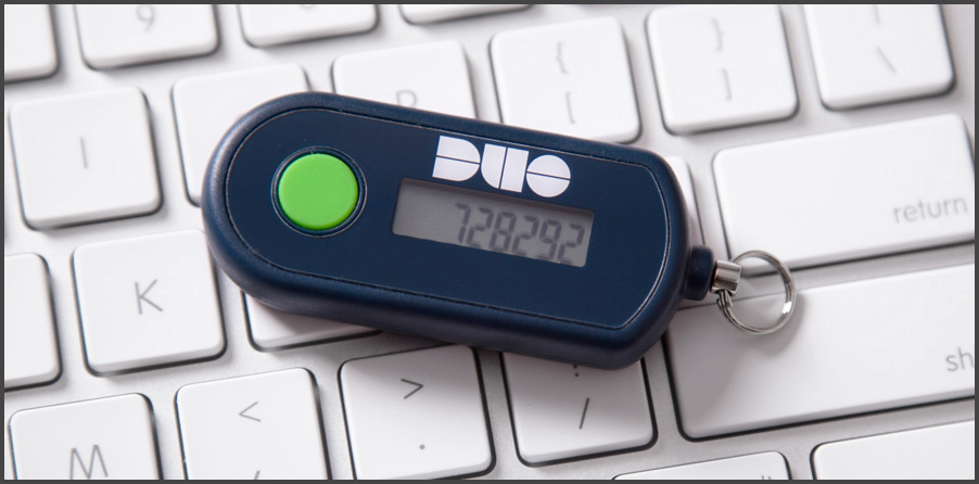 Duo Hardware Token example image – blue body base with DUO tag on top with an analog screen revealing a 6-digit code “728292” with green button over an Apple Keyboard