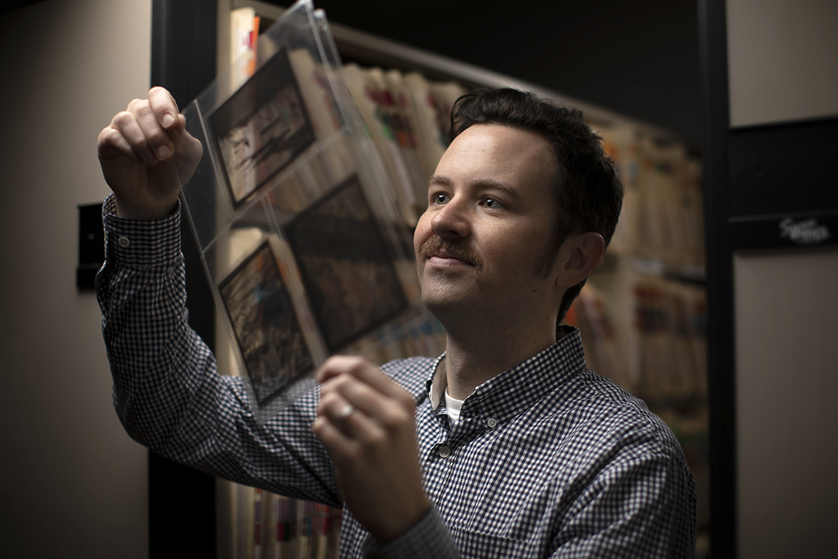 CMC Archivist Sean Stanley holding up photos from the school archive