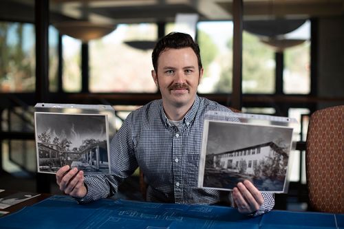 CMC Archivist Sean Stanley holds up photographs of CMC's early history