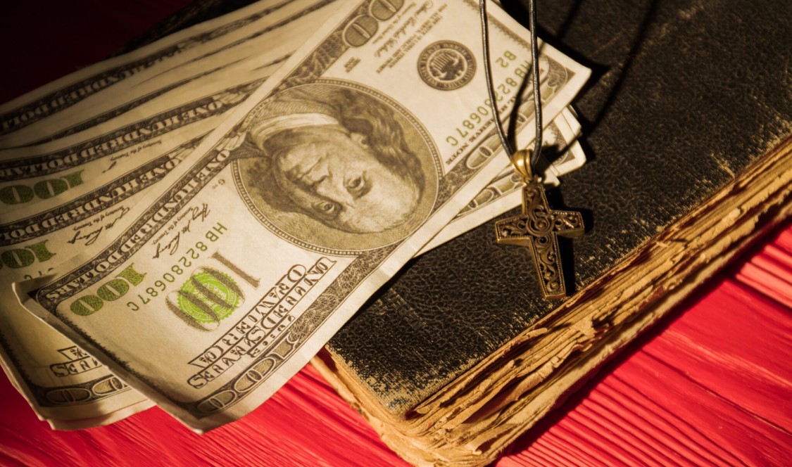 money, a crucifix necklace on an old book