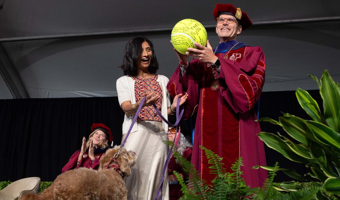 Pres. Chodosh holding large tennis ball with Priya Junnar and Theo