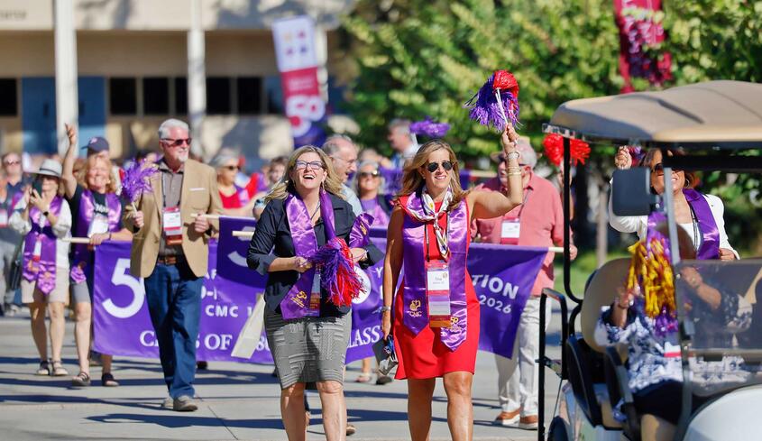 Group of people marching down the campus mall celebrating 50 Years of Co-ed at Impact weekend