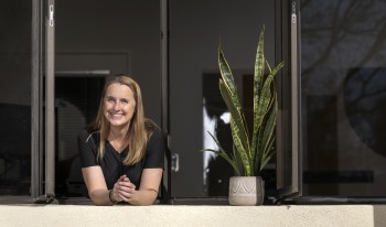 DT leans out of the open window in her office next to her snake plant.