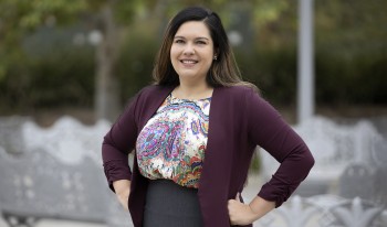 Portrait of CMC Prof. Jennifer Feitosa with her arms akimbo on campus.