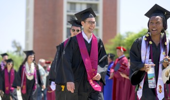 Smiling graduates of the classes of 2020 and 2021 file into the commencement tent on Parents Field as faculty welcome them.