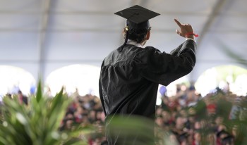 A CMC grad waves to the crowd inside the white tent after they walked the commencement stage during Classes of 2020 &amp; 2021's Celebration Weekend.
