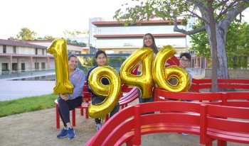 Students near the Jeppe Hein benches hold giant gold balloons spelling out &quot;1946&quot;