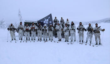 Men in military uniforms holding flags and rifles standing in snow.