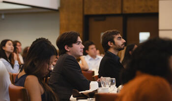 Students sitting at round table conversing. 