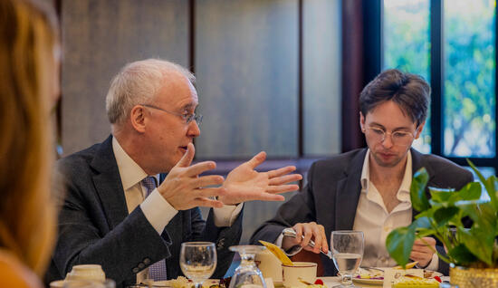 Man in black suit talking to student at lunch seminar in Athenaeum.