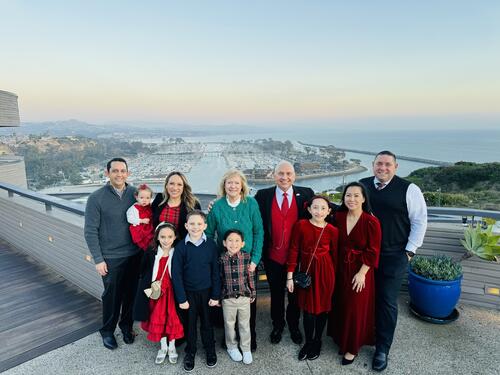 Family of ten a mix of children and adults posing for a photo on a rooftop location overseeing the city. 