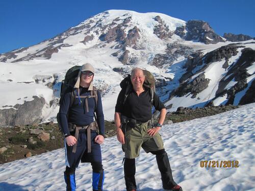 Two men hiking in snowy mountains with mountains in background.