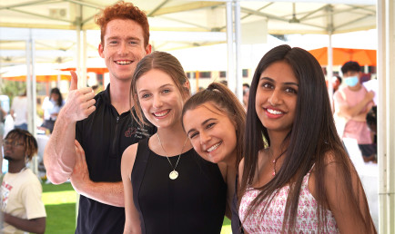 Four students smile together for the camera at the SIF booth during the Club and Institute Fair