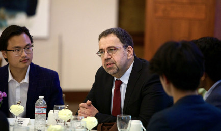 MIT Applied Economics Professor Daron Acemoglu sits at the head table inside the Ath main room.