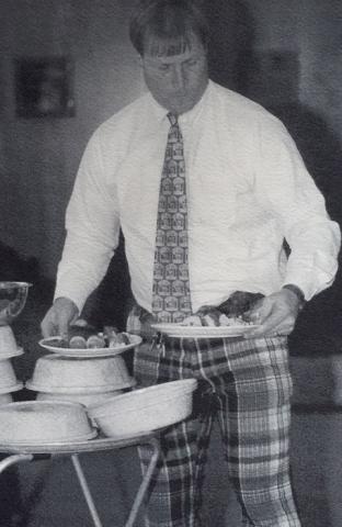 Black and white photo of David Edwards serving hot plates of food at an Ath event.
