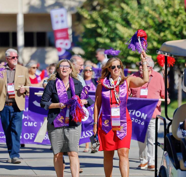 Group of people marching down the campus mall celebrating 50 Years of Co-ed at Impact weekend