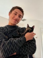 Portrait of MJ Lindsey holding their cat Artemis.