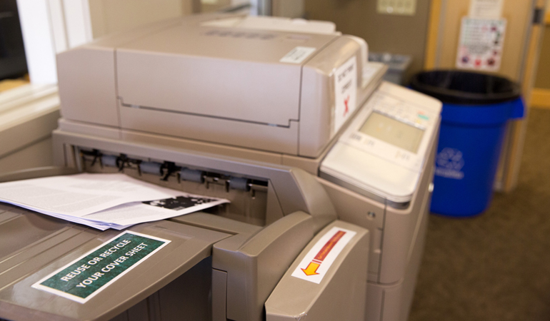 Sign on printer encouraging waste reduction